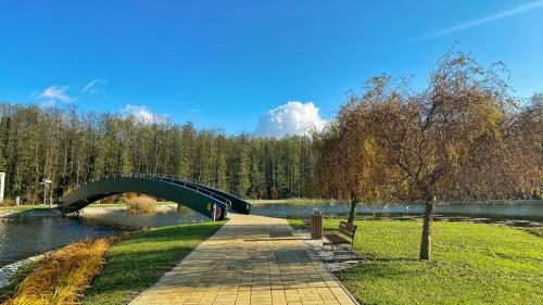 a bridge over a river with a bench in a park at Kala Thermal Lake Wellness Apartment in Zalakaros