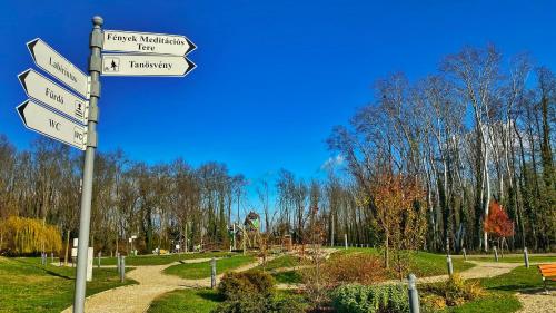 a street sign with several signs in a park at Kala Thermal Lake Wellness Apartment in Zalakaros