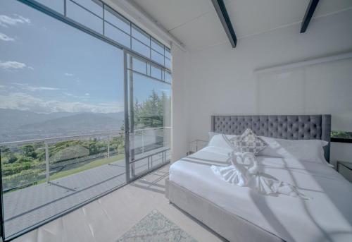 a bedroom with a bed and a large window at Mountain Mansion Pool, Jacuzzi Epic Medellin View in Envigado