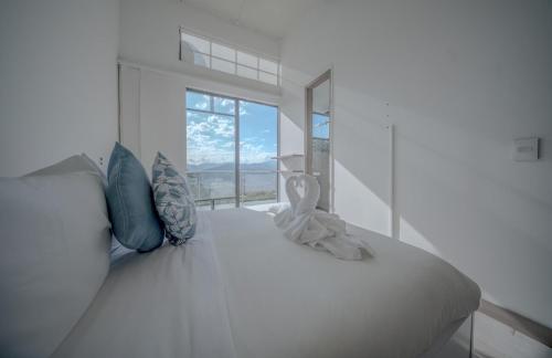 a bedroom with a white bed with a large window at Mountain Mansion Pool, Jacuzzi Epic Medellin View in Envigado
