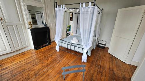 une chambre avec un lit avec des rideaux et un parquet dans l'établissement Les Jardins de Baudimont 4p apartment, à Arras