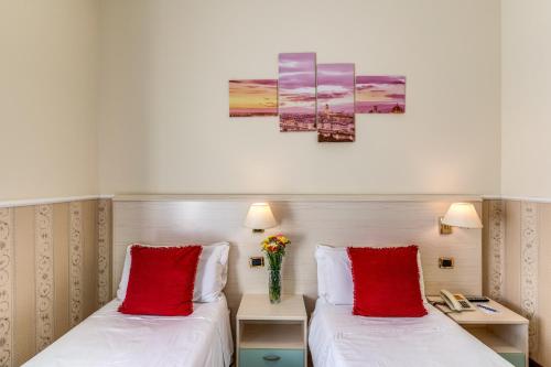 two beds in a hotel room with red pillows at Hotel Ottaviano Augusto in Rome