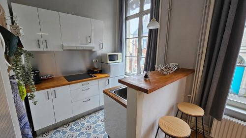 - une cuisine avec des placards blancs, un évier et des tabourets dans l'établissement Les Jardins de Baudimont 4p apartment, à Arras