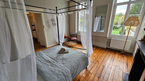 - une chambre avec un lit à baldaquin et du parquet dans l'établissement Les Jardins de Baudimont 4p apartment, à Arras
