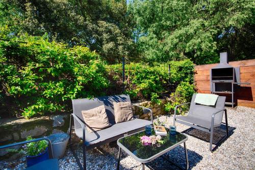 a patio with two chairs and a table and a grill at Can Cruanyes in Sales del Llierca