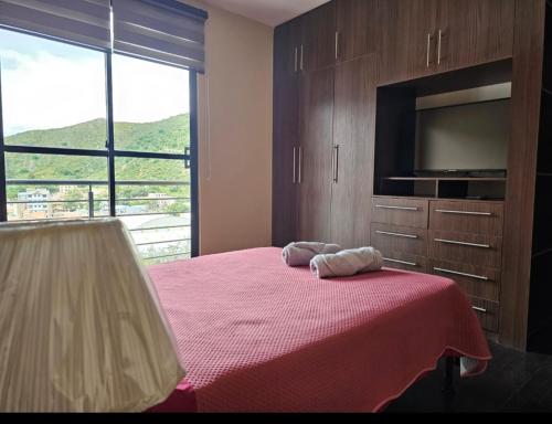 una camera da letto con un letto con una tv e una grande finestra di El Cristo a Cochabamba