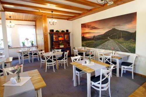 a restaurant with tables and chairs and a painting on the wall at Willa 1910 in Karpacz