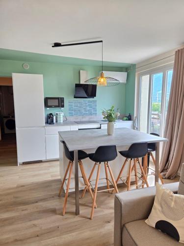 une cuisine et un salon avec une table et des chaises dans l'établissement L'Acacia T2 tout confort avec clim WiFi vue tram, à Grenoble