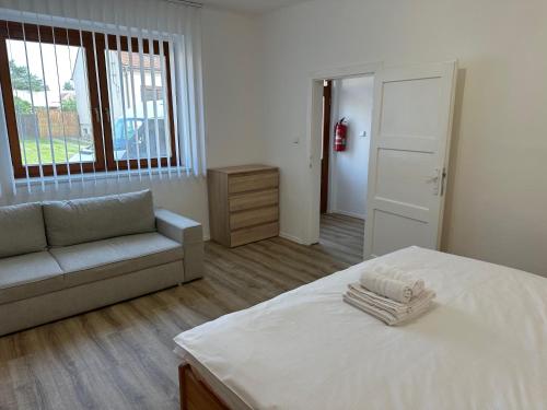 a bedroom with a bed and a couch and a window at Penzion Trödler in Brod nad Dyjí
