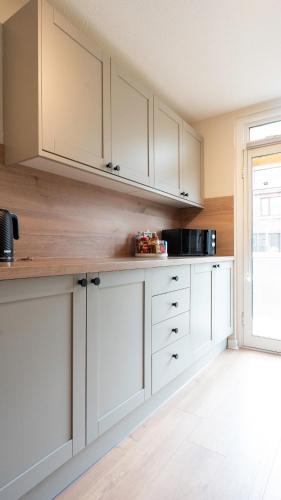 a kitchen with white cabinets and a window at Tummel Place in Grangemouth