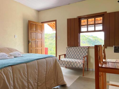 a bedroom with a bed and a chair and a window at Pousada Paraíso in Lavras Novas