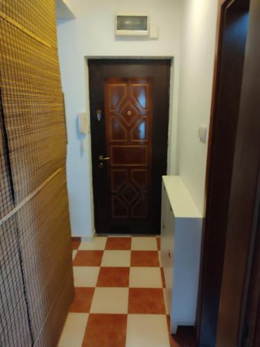 a hallway with a wooden door and a checkered floor at Una apartmani Petrovac in Petrovac na Moru