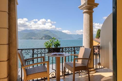 a balcony with a table and chairs and a view of the water at Hotel Royal Victoria, by R Collection Hotels in Varenna