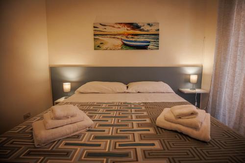 una camera da letto con un letto grande con asciugamani sopra di Soffio di Mediterraneo appartamento a Trapani