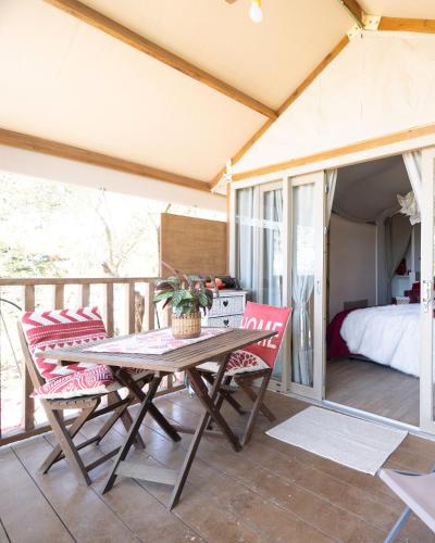 a table and chairs on a balcony with a bed at Ciriga Sicily Glamping in Santa Maria Del Focallo