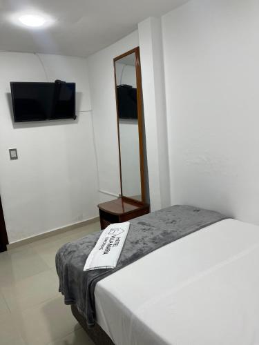 a room with a bed and a flat screen tv at Hotel Villa María Coworking in Villavicencio