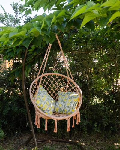 a wicker chair hanging from a tree at Ciriga Sicily Glamping in Santa Maria Del Focallo