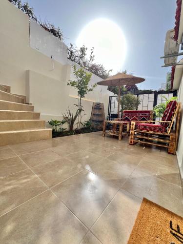 a patio with chairs and an umbrella and stairs at Villa 2, Modern Charm Facing Carrousel with Ocean View in Rabat