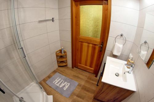 a bathroom with a shower and a sink and a door at Willa 1910 in Karpacz