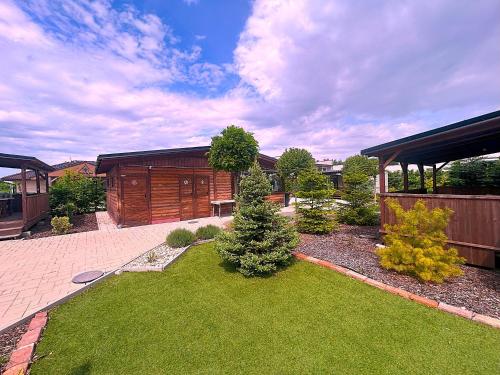 a backyard with a yard with green grass and trees at Domčeky Nesvady in Nesvady