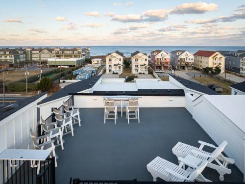 a balcony with a table and chairs and the ocean at New Build with Rooftop Deck & Panoramic Ocean Views in Kill Devil Hills
