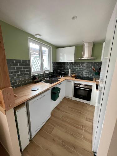 une cuisine avec des armoires blanches, un évier et une fenêtre dans l'établissement Maison cosy avec jardin & parking, proche Disney, à Chelles