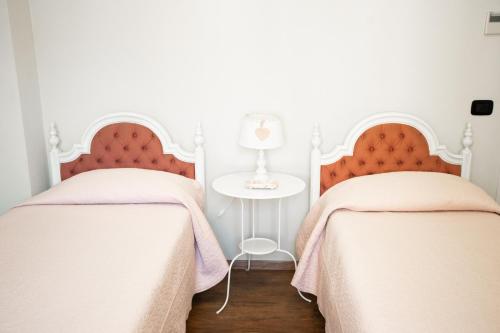 two beds in a white room with a table at Residence Cà di Capri in Bussolengo