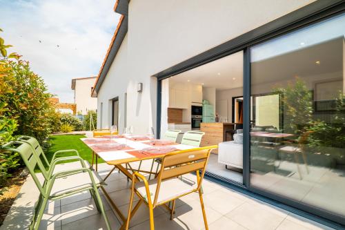 - une table à manger et des chaises sur une terrasse avec des portes en verre dans l'établissement Villa Parenthèse - Élégance & Confort - clim, à Perpignan