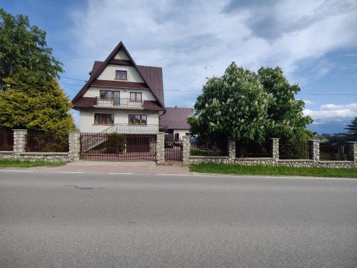 a house with a fence in front of a street at Pawlikówka in Zakopane
