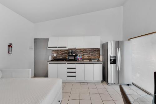a kitchen with white cabinets and a stainless steel refrigerator at Bella Surf Inn in Isabela
