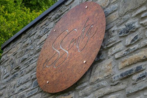 a wooden sign on the side of a brick wall at Essentia Guest House in Faggeto Lario 