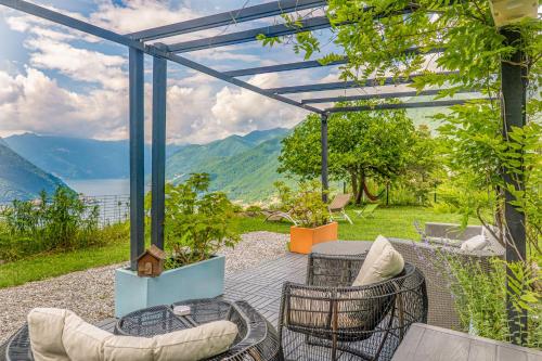 a patio with furniture and a view of the mountains at Essentia Guest House in Faggeto Lario 