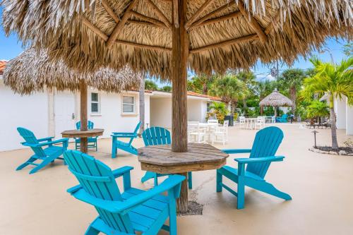 a group of blue chairs and tables under a straw umbrella at Bianco Sands By Beachside Management in Siesta Key