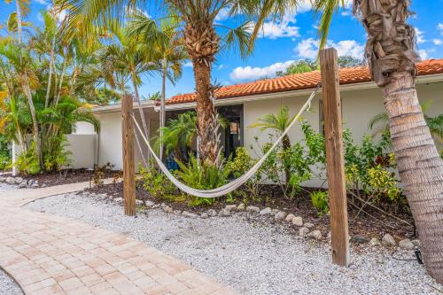 a house with palm trees and a hammock in front of it at Bianco Sands By Beachside Management in Siesta Key