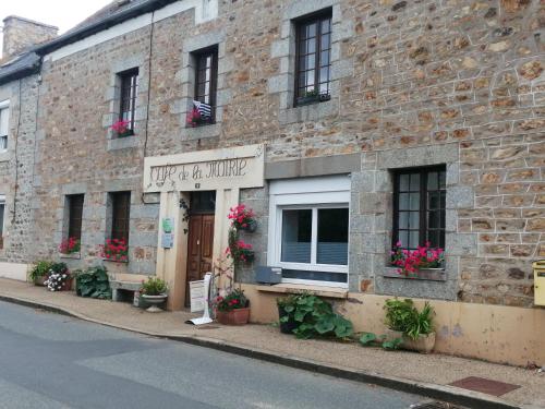 un bâtiment en briques avec des fleurs dans la fenêtre dans l'établissement SUITE DE LA FONTAINE Café de la mairie, à Gommenec'h