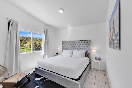 a white bedroom with a bed and a window at Bella Surf Inn in Isabela