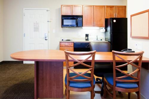 a kitchen with a wooden table and two chairs at Candlewood Suites New Bern by IHG in New Bern