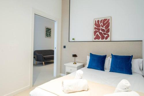 a bedroom with a large white bed with blue pillows at Apt new Mestalla | jacuzzi | billar | ping pong in Valencia
