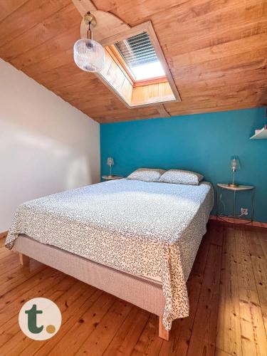 une chambre avec un lit et un mur bleu dans l'établissement Tranquiloue - Maison de Campagne Proche Puy du Fou, à Tiffauges