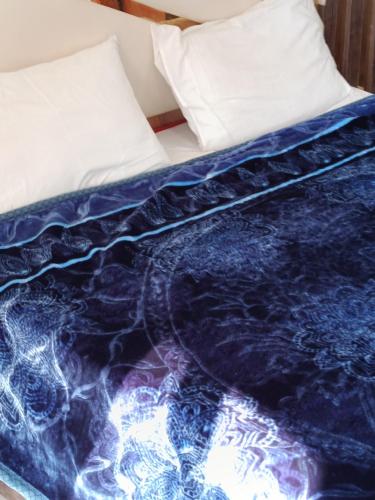 a bed with a blue comforter and a pillow at Holiday Bhurban in Murree