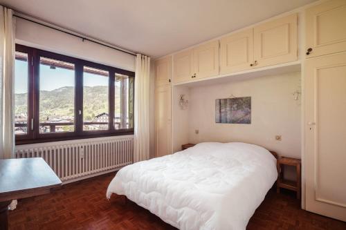 une chambre avec un lit blanc et une grande fenêtre dans l'établissement Le Central - In the heart of Megève, à Megève