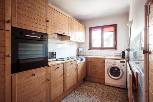 une cuisine avec des armoires en bois et une laveuse et une sécheuse dans l'établissement Le Central - In the heart of Megève, à Megève