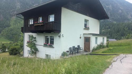 ein weißes Haus mit Balkon und Stühlen auf einem Hügel in der Unterkunft Haus Unterberger in Heiligenblut