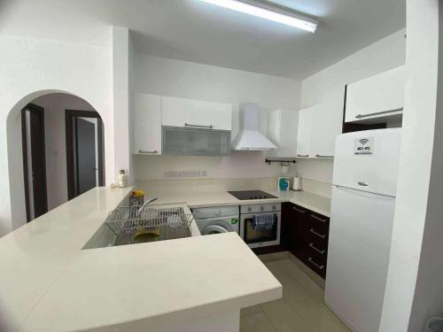 a white kitchen with a sink and a refrigerator at Aphrodite gardens 2 bedroom in Paphos City