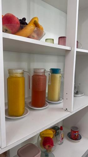 a shelf with four jars of different colored liquids at Pousada Musa do Porto in Porto De Galinhas