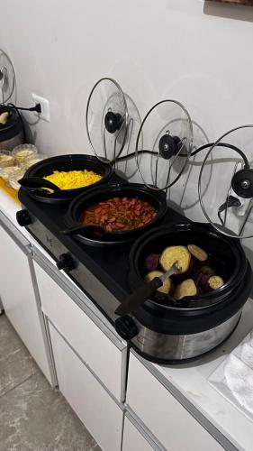 a stove top with three pans of food on it at Pousada Musa do Porto in Porto De Galinhas
