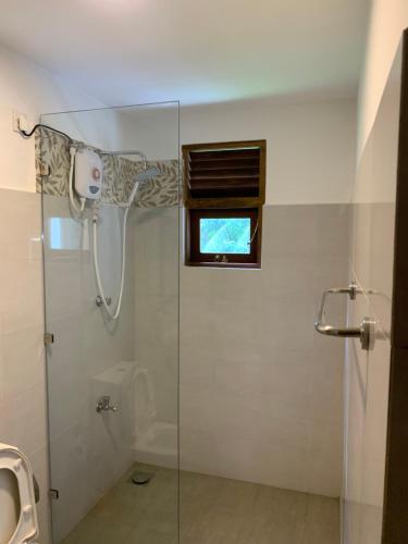 a bathroom with a glass shower with a window at Serene Deck Kadawatha in Kadawatha