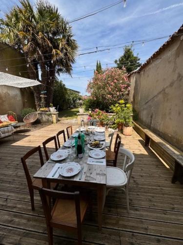 - une table avec des chaises et des assiettes de nourriture sur la terrasse dans l'établissement Villa familiale proche océan, à Marennes