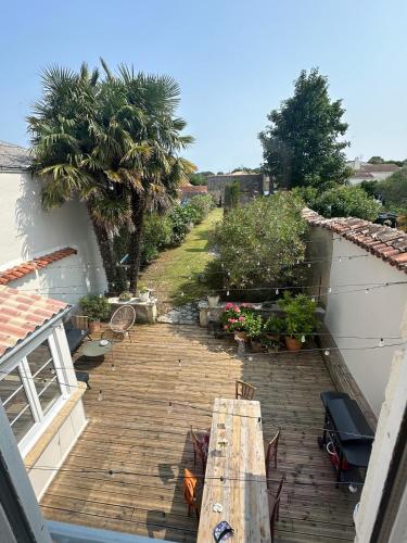 un patio extérieur avec une table et des chaises en bois dans l'établissement Villa familiale proche océan, à Marennes