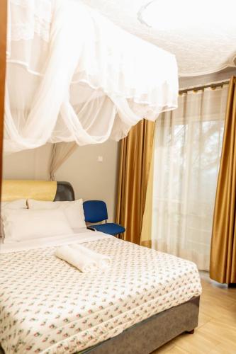 a bedroom with a bed with white sheets and curtains at Jebel Hotel & Lounge Buloba in Kampala